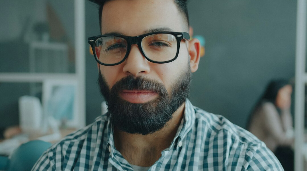 Portrait of a young Croatian man with a short beard and glasses smiling